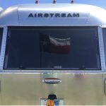 Texas Flag framed in the back window of an Airstream Travel Trailer.